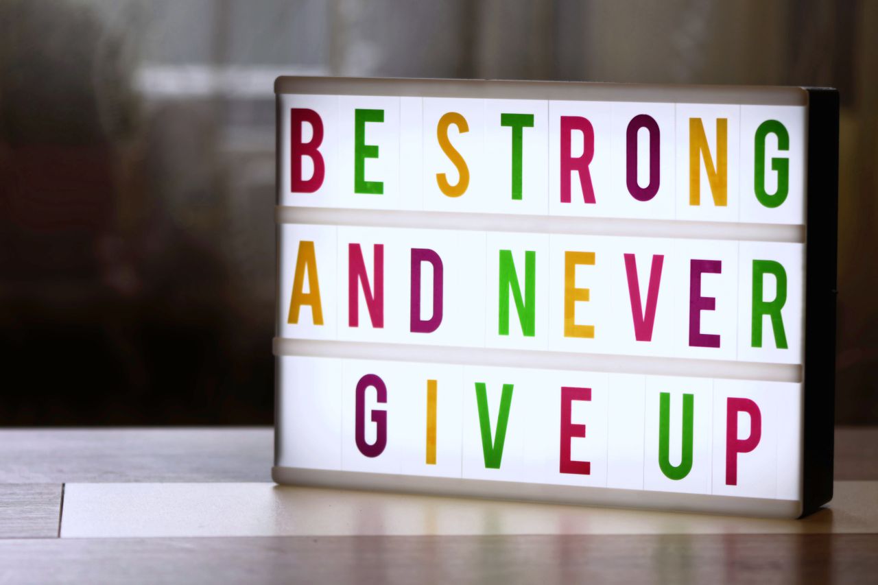 Motivational lightbox sign displaying 'Be Strong and Never Give Up.'